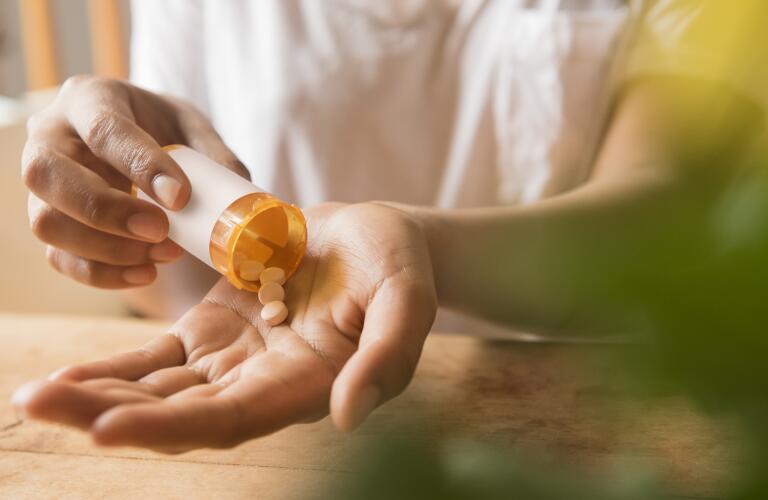 Close-up of woman's hand taking prescription medication pills