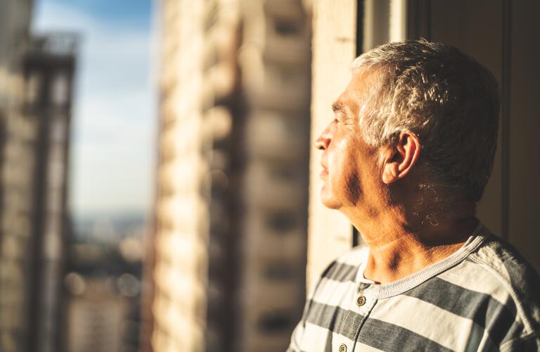 concerned senior man looking through window