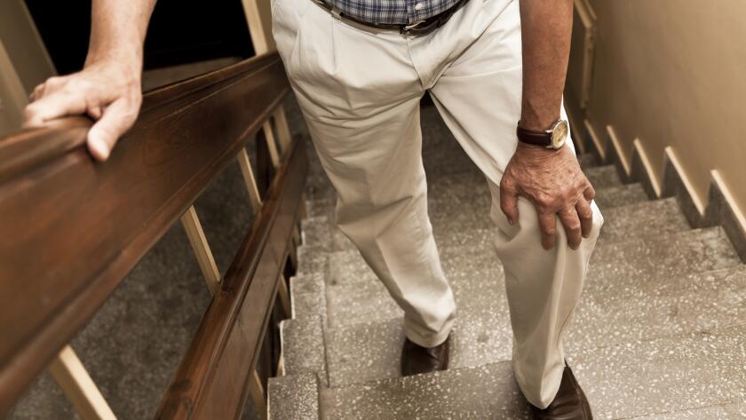 Unseen older man experience knee pain on stairs