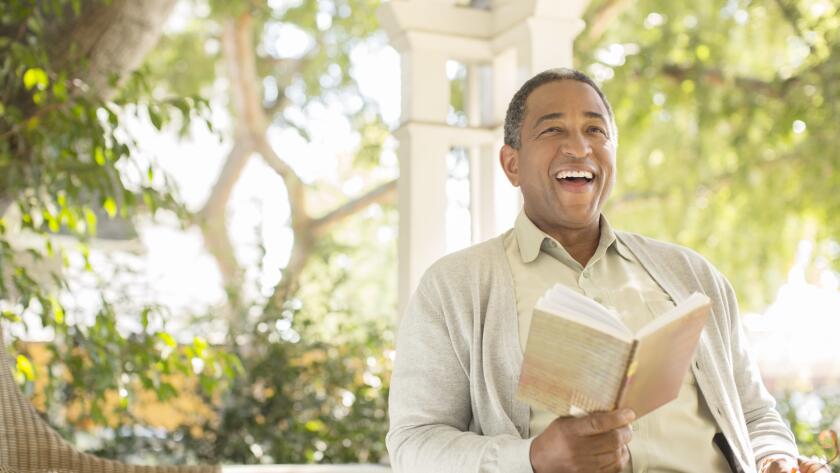 laughing-senior-man-reading-on-porch