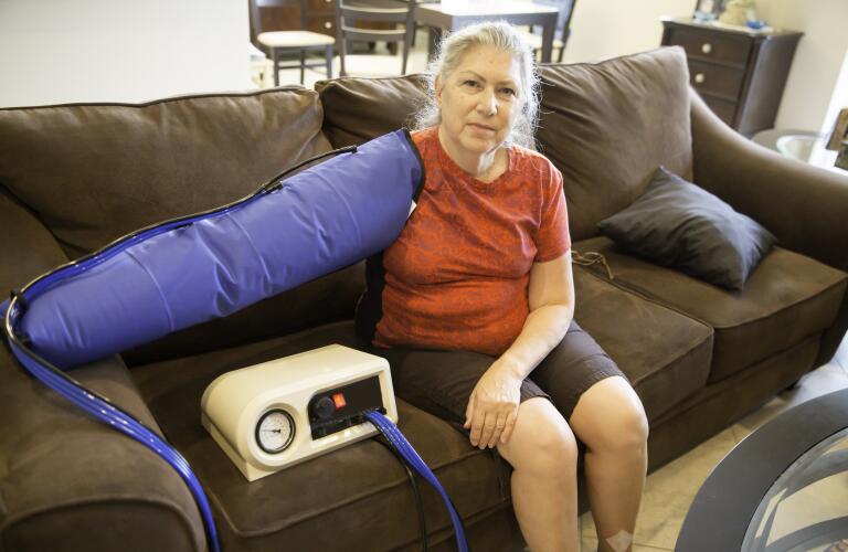 Senior woman using pressure pump for lymphedema in arm