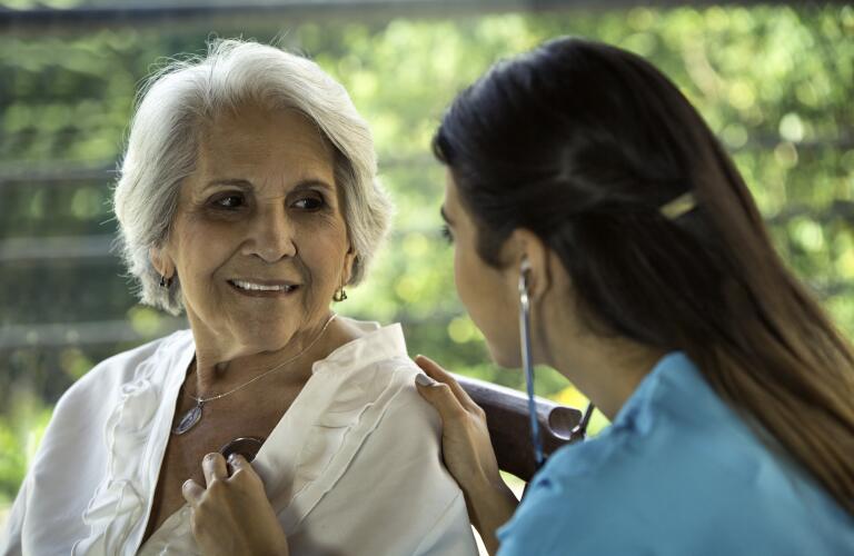 Female physician listens to senior patient's heart