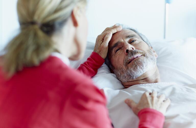 Woman caressing ill man in hospital ward