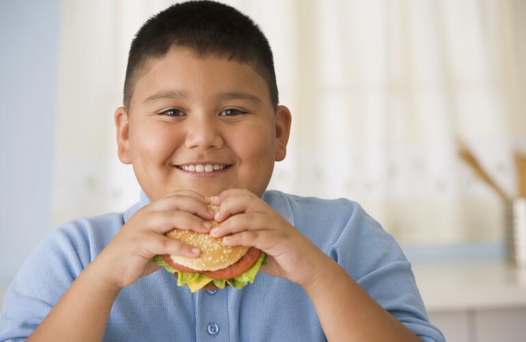 boy eating hamburger in kitchen