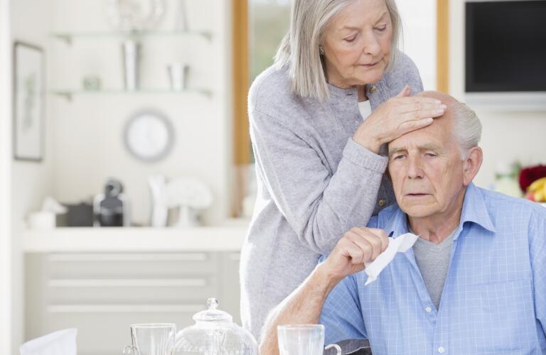 Older woman feeling sick husband's forehead