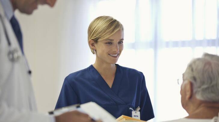 Doctor and nurse talking to older patient in hospital room