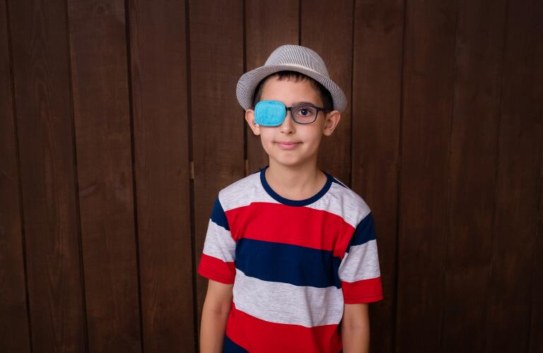 Portrait of boy in glasses with patch. Eye patch for glasses to treat lazy eye, amblyopia, strabismus.