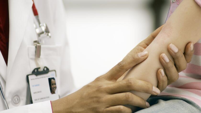 doctor examining girl's rash on her inner elbow