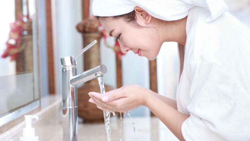 Portrait of young woman washing her face