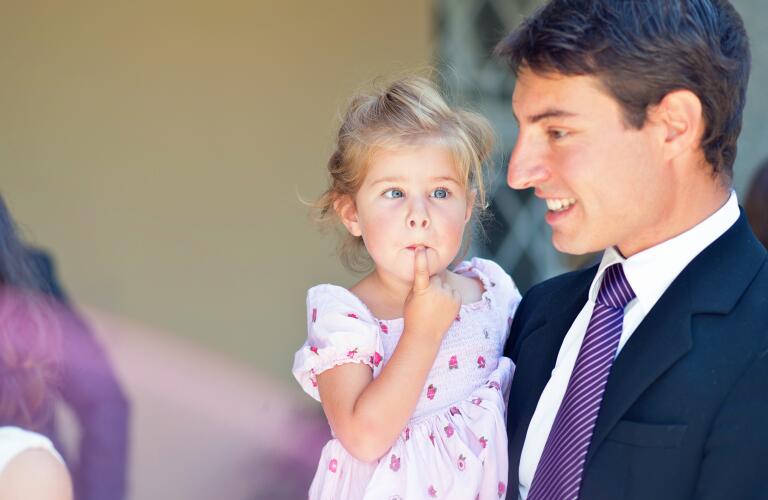 Little girl with strabismus in eye being held by her father
