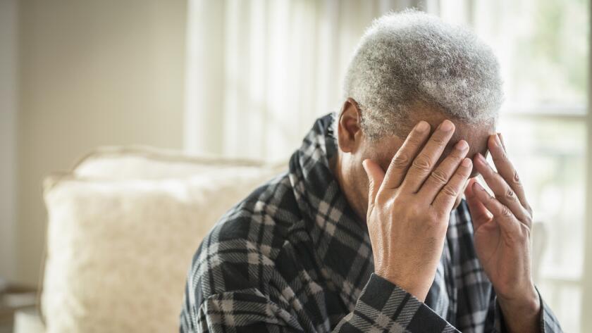 disoriented African American senior male with head in hands