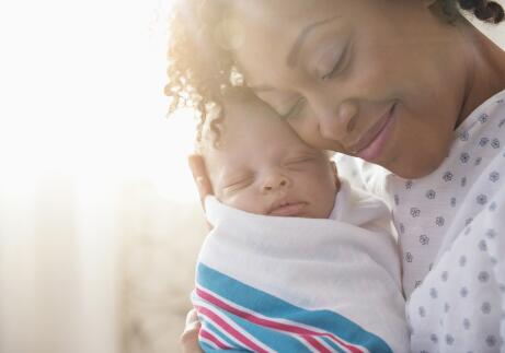 Mother with newborn infant smiling with eyes closed