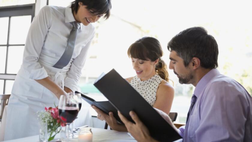 Waitress taking order from professional couple in restaurant