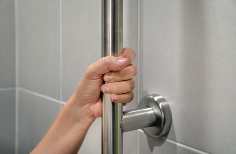 closeup of hand holding onto shower grab bar