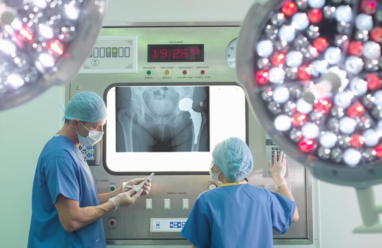 Two surgeons looking at X-ray of artificial hip joint in operating room