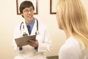 Male doctor with female patient holding clipboard